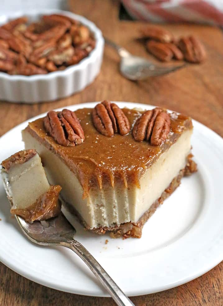 paleo vegan caramel pecan cheesecake with a bite taken out and set to the side