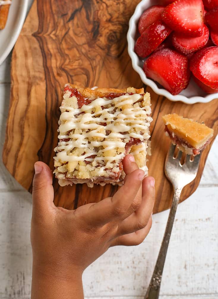 small hand reaching for a paleo strawberry crumb bar