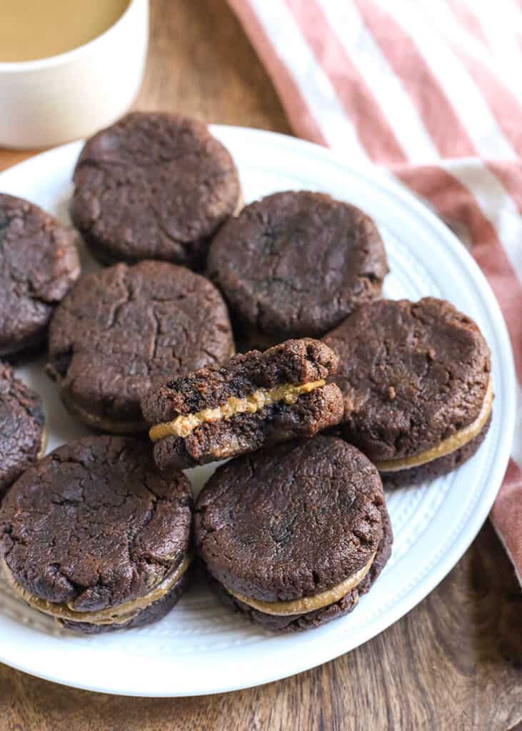 a plate of paleo chocolate sandwich cookies with a bite taken out of one