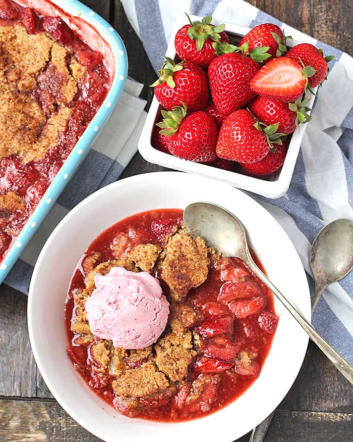 Paleo Strawberry Cobbler in a bowl with strawberry ice cream on top. 