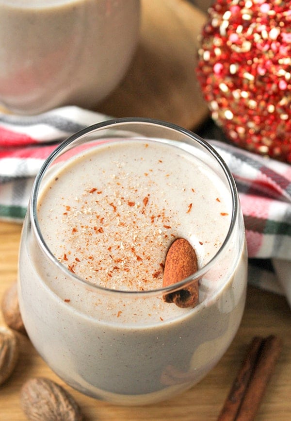 Homemade eggnog in a glass with a cinnamon stick in it. 