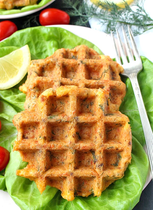 close view of salmon cake waffles on a lettuce bed with a fork on the right side. 