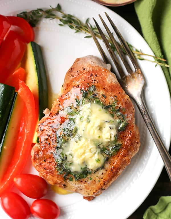 These Paleo Whole30 Pork Chops with Herbed Butter make a quick weeknight meal. Tender, juicy pork chops topped with an easy butter filled with fresh herbs. Gluten free, low carb, and keto.