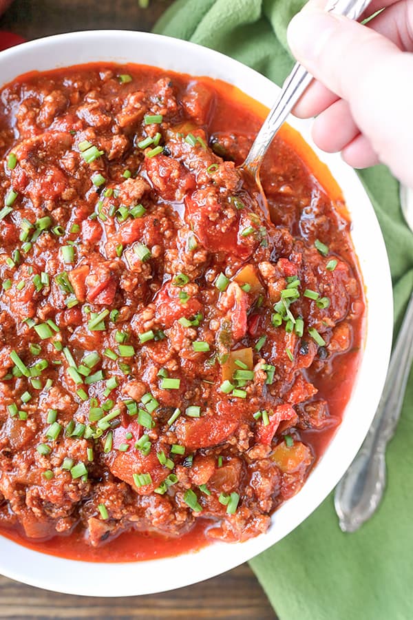 A bowl of bean-less chili with chives on top. 