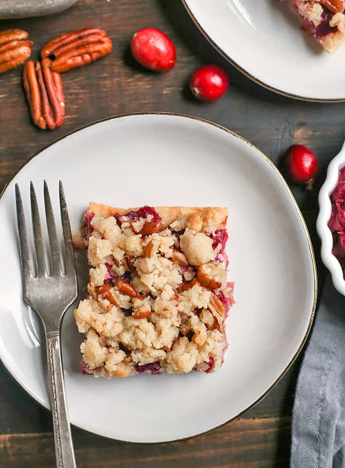These Paleo Vegan Cranberry Crumb Bars are simple to make and so delicious! A shortbread crust, thick layer of cranberry sauce and then a delicious crumb topping. They are gluten free, dairy free and naturally sweetened.