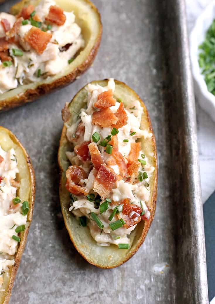 A close shot on a potato skin topped with bacon and chives. 