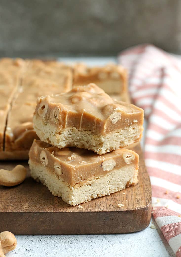 These Paleo Caramel Cashew Bars are easy to make, rich, and so good! A shortbread layer topped with a fudge-like layer that is sweet and packed with buttery cashews. They are gluten free, dairy free, vegan, and naturally sweetened.