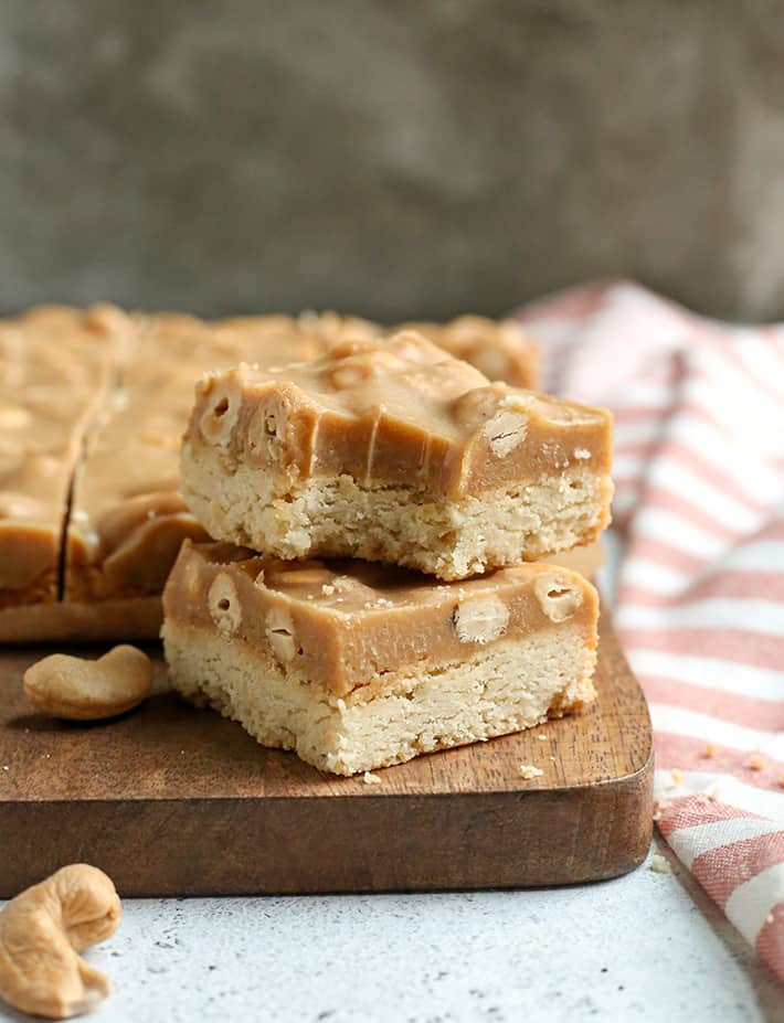 These Paleo Caramel Cashew Bars are easy to make, rich, and so good! A shortbread layer topped with a fudge-like layer that is sweet and packed with buttery cashews. They are gluten free, dairy free, vegan, and naturally sweetened.