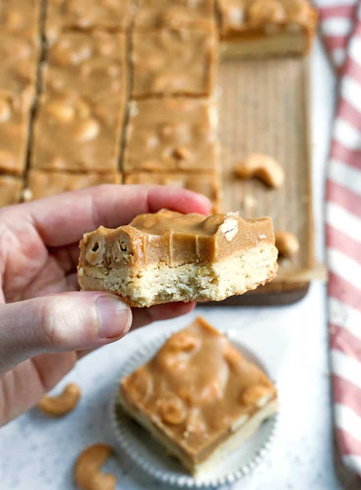 These Paleo Caramel Cashew Bars are easy to make, rich, and so good! A shortbread layer topped with a fudge-like layer that is sweet and packed with buttery cashews. They are gluten free, dairy free, vegan, and naturally sweetened.