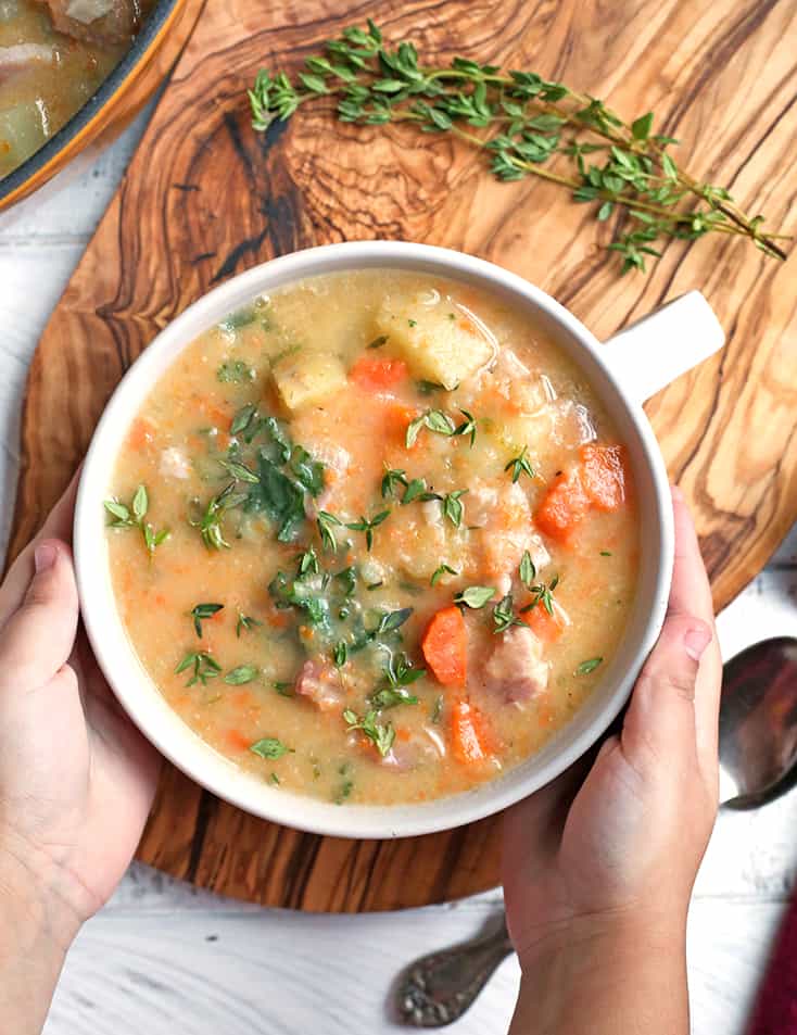 ham and potato soup with little hands holding the bowl