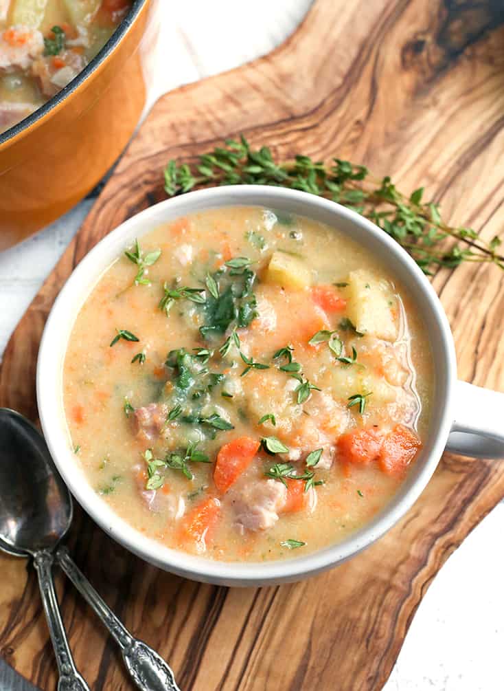 ham and potato soup in a bowl with spoons next to it