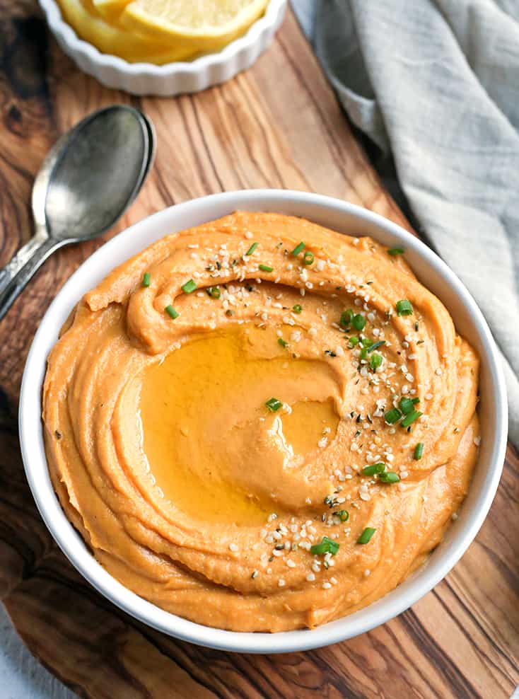 paleo hummus is a bowl with a spoon behind it