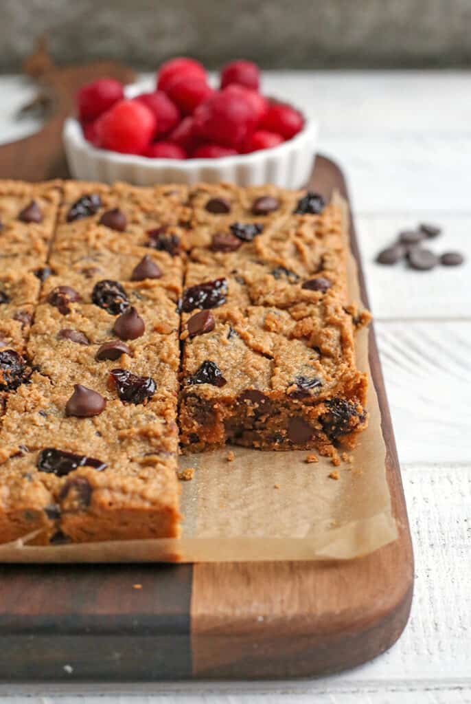 a board with paleo cherry chocolate chips bars on it. One is removed so the inside is showing. 