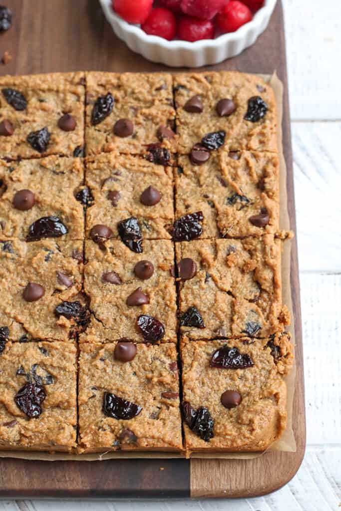 paleo cherry chocolate chips bars on a cutting board, cut into squares