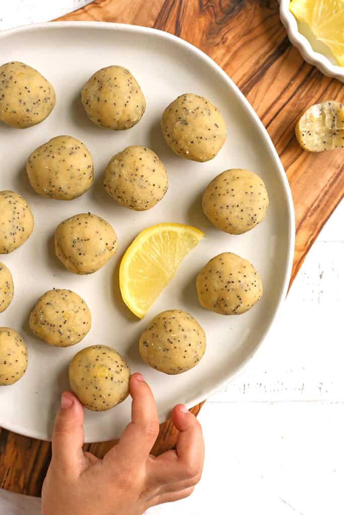 a little hand picking up a paleo vegan lemon poppy seed bite