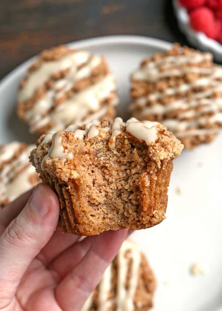 hand holding a bite taken out of a paleo coffee cake muffin