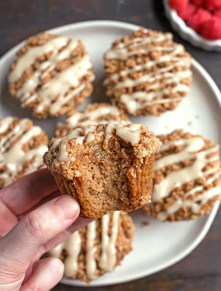 paleo coffee cake muffins, one in a hand with a bite taken out of it