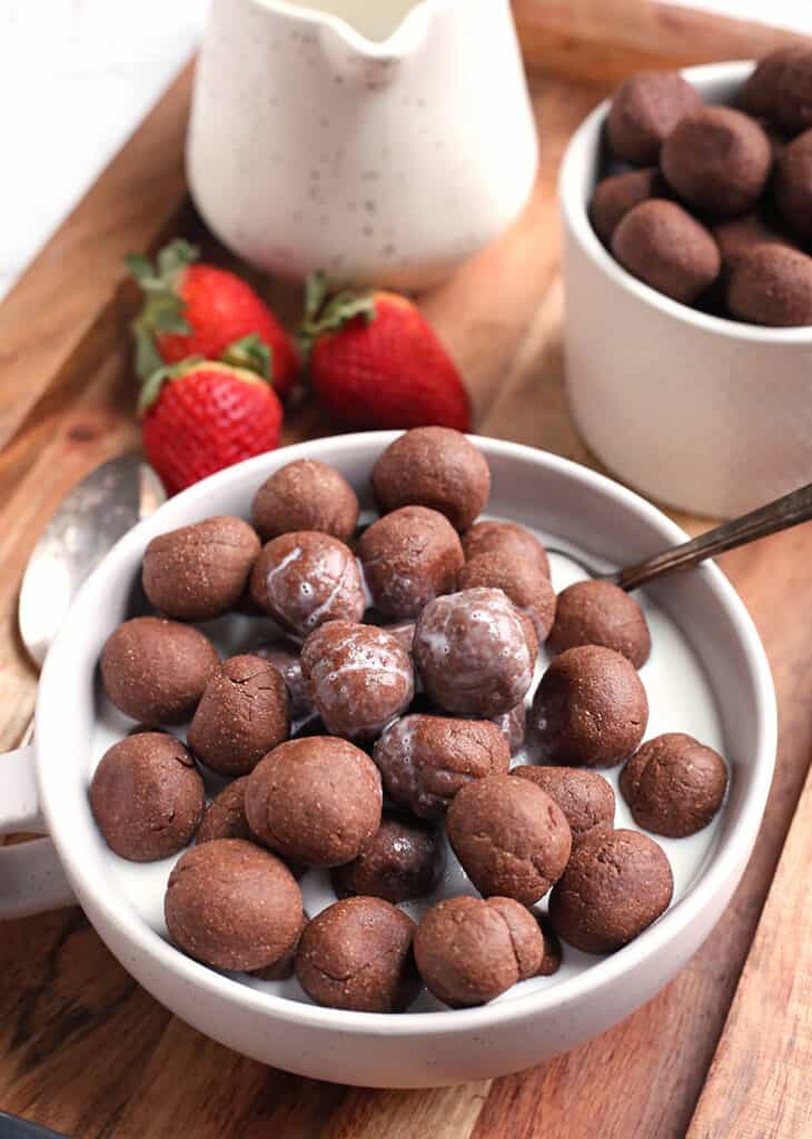 paleo nut free cocoa puffs cereal in a bowl with almond milk and a spoon in the bowl