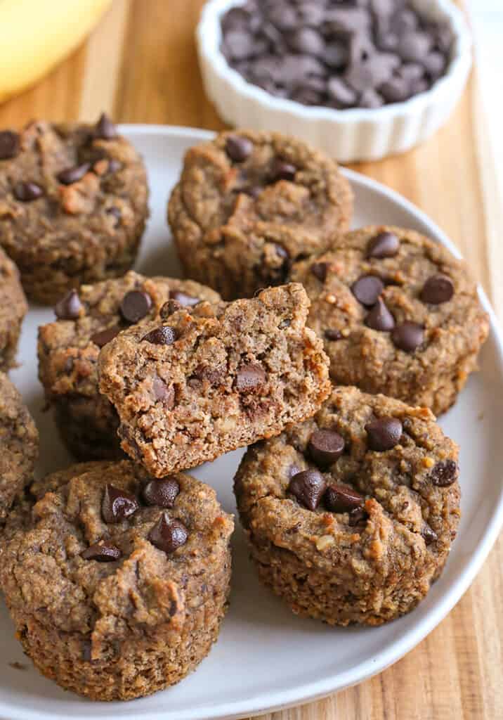 a plate with vegan paleo banana muffins on it. One is cut so the center is showing. 