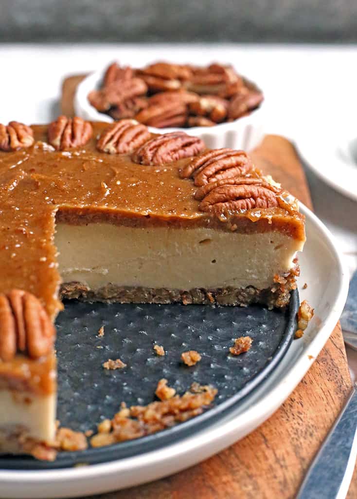 paleo vegan caramel pecan cheesecake with a slice removed, inside is showing