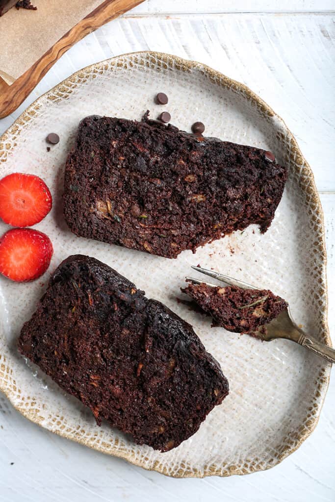 2 slices of paleo vegan chocolate zucchini bread on a plate. A bite taken out of one. 