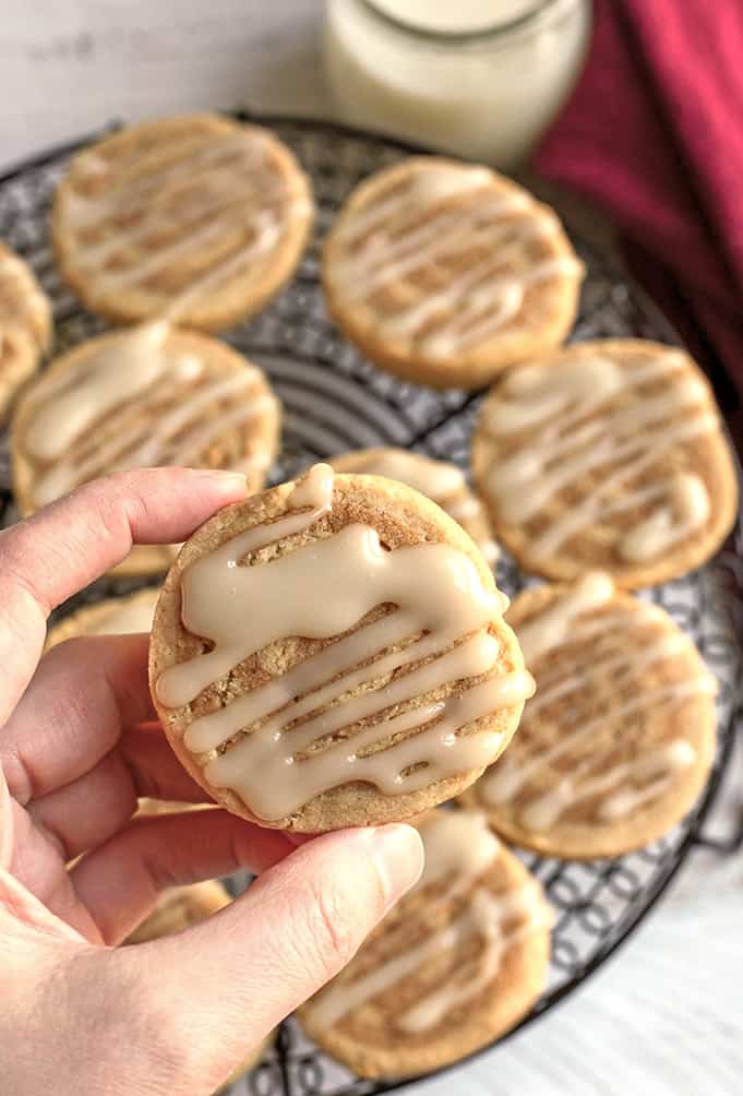 hand holding a paleo cinnamon roll cookie showing the top with icing 