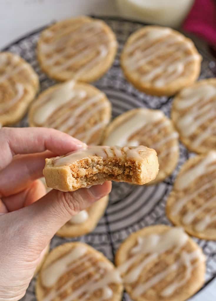 hand holding a cinnamon roll cookie with a bite taken out 