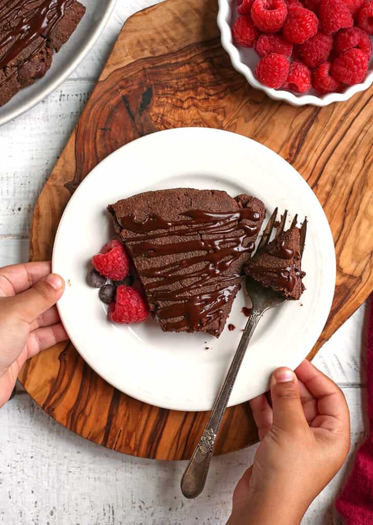 little hands holding a plate with a paleo triple chocolate scone on it