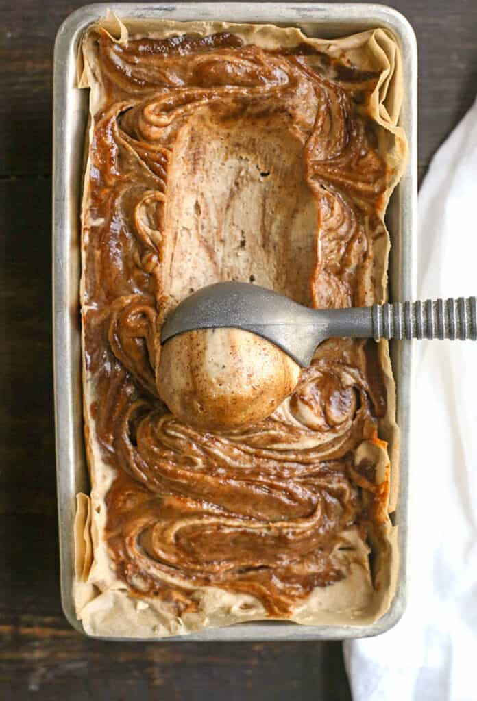 paleo vegan cinnamon roll ice cream with a scoop being taken out of it