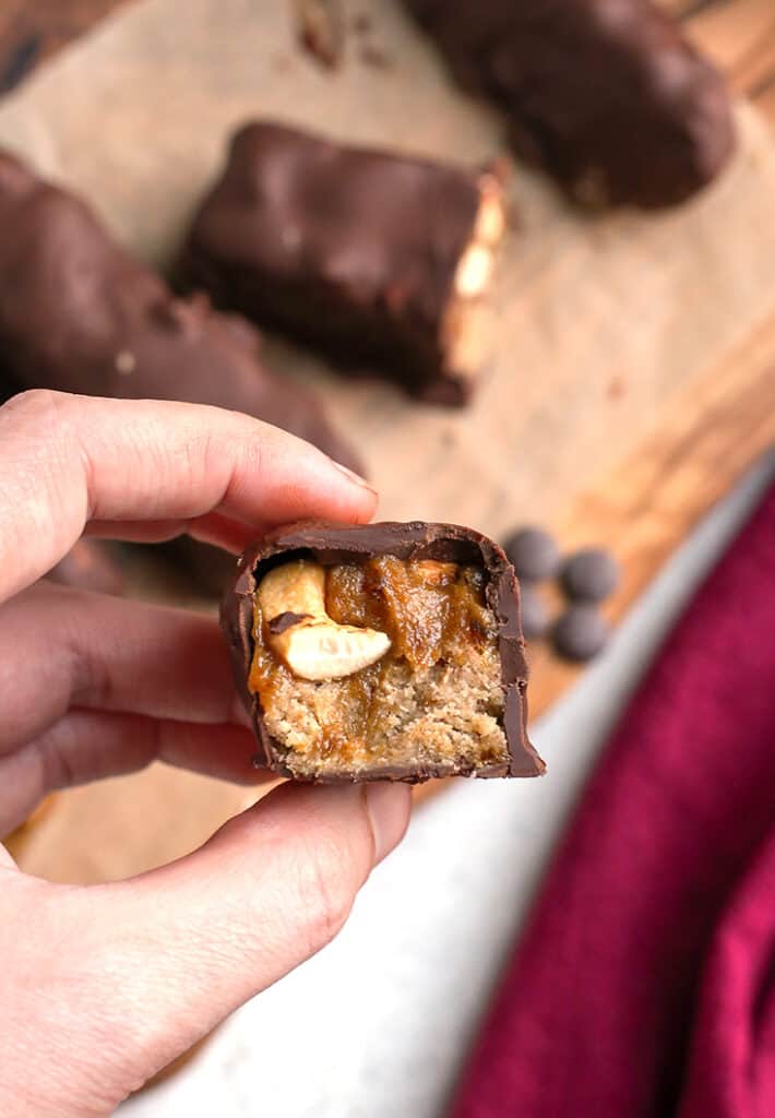 paleo vegan snickers bar being held by a hand, inside showing