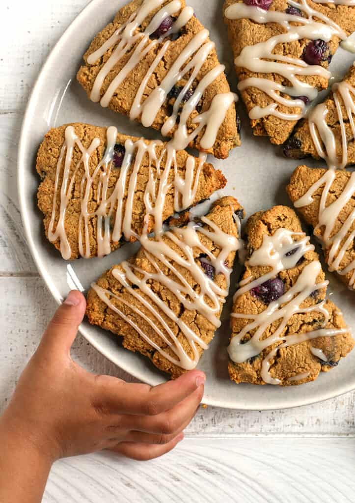 a little hand reaching for a paleo blueberry scone