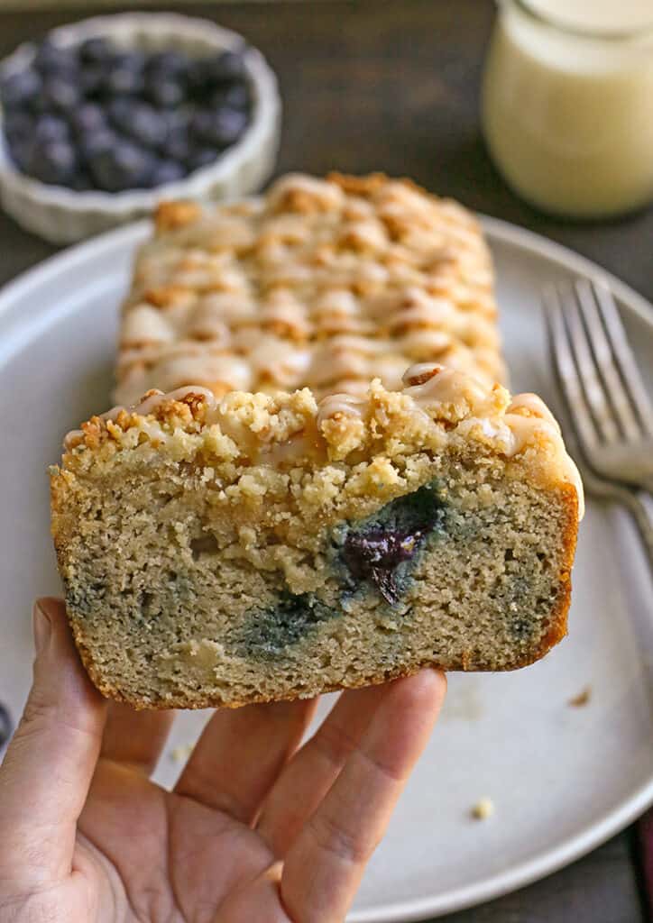 hand holding a piece of paleo blueberry streusel bread 