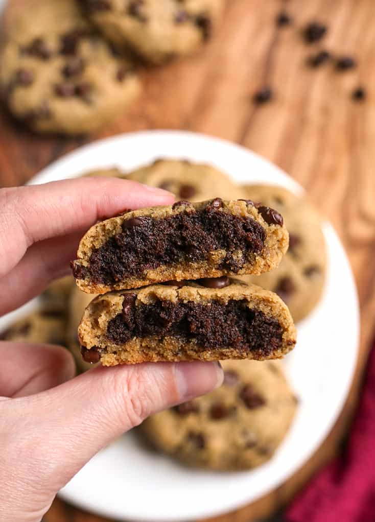 hand holding a paleo vegan brownie stuffed chocolate chip cookie with the inside showing 
