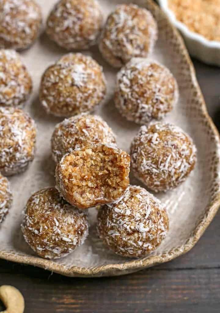 cashew coconut bites on a plate with a bite taken out of one 