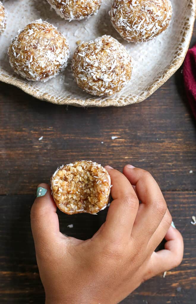 a little hand holding a paleo coconut cashew bite 