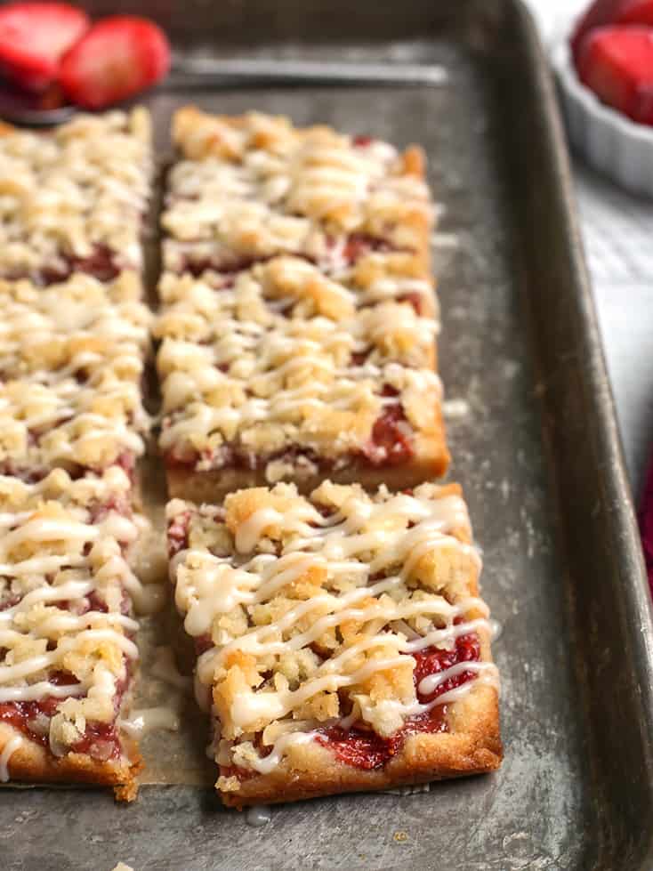 strawberry crumb bars on a pan, cut with drizzle on top