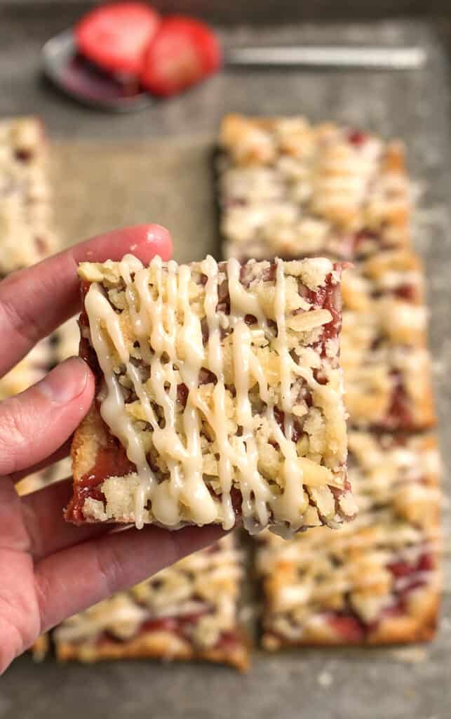 a hand holding a paleo strawberry crumb bars showing the top