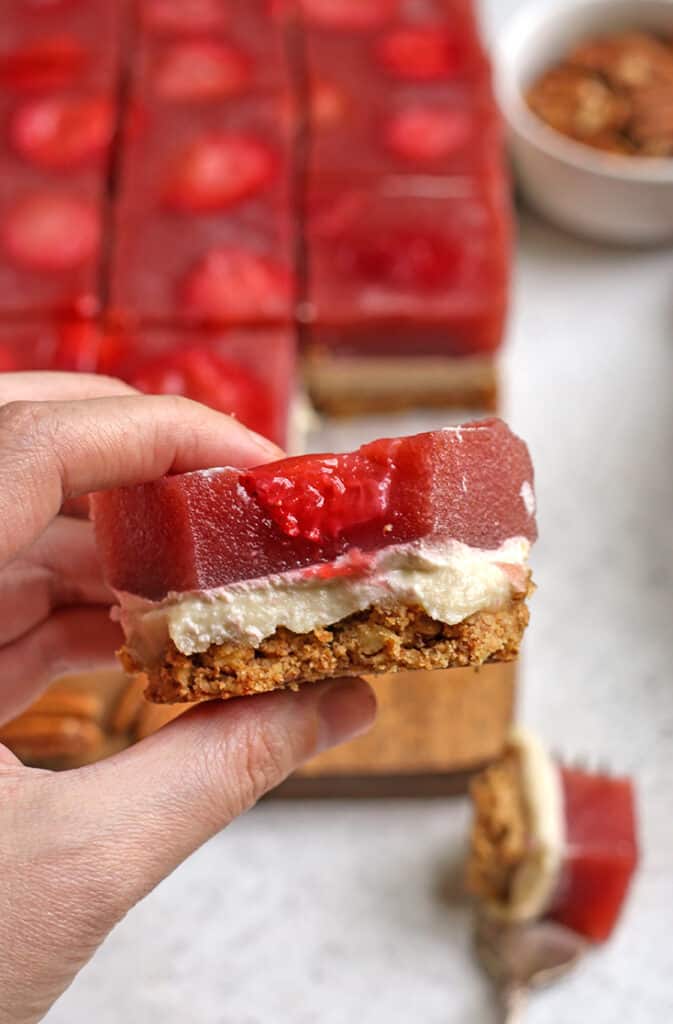 hand holding a piece of paleo strawberry pretzel salad with a bite taken out 