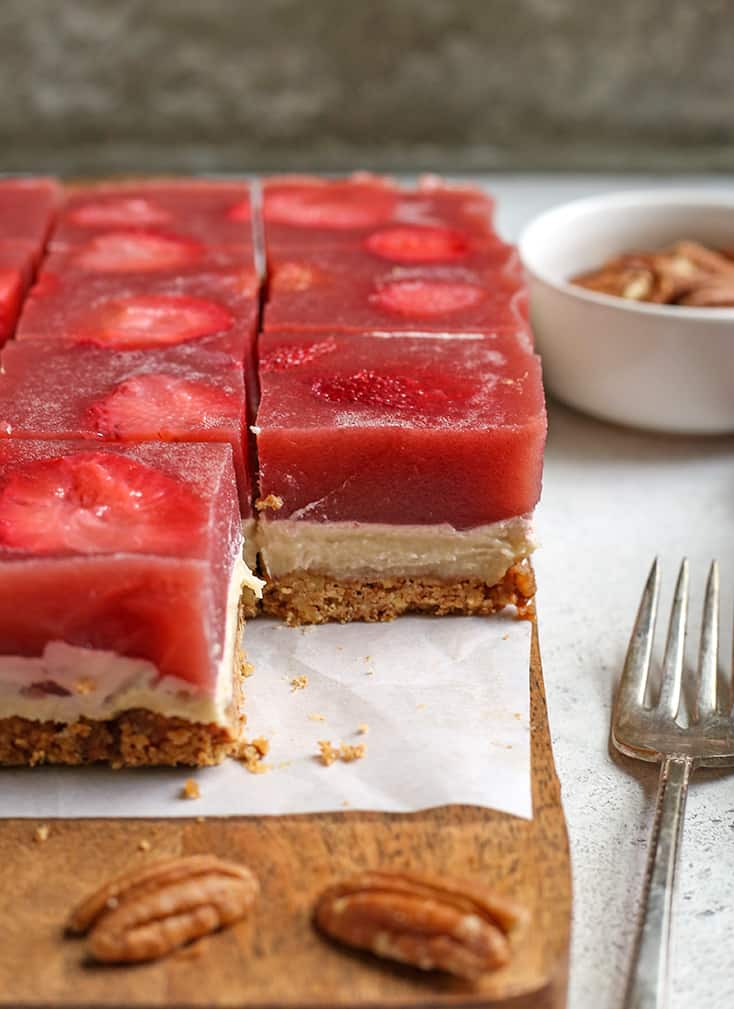 slices of paleo strawberry pretzel salad. One piece removed to show the layers of crust, cream cheese and gelatin. 