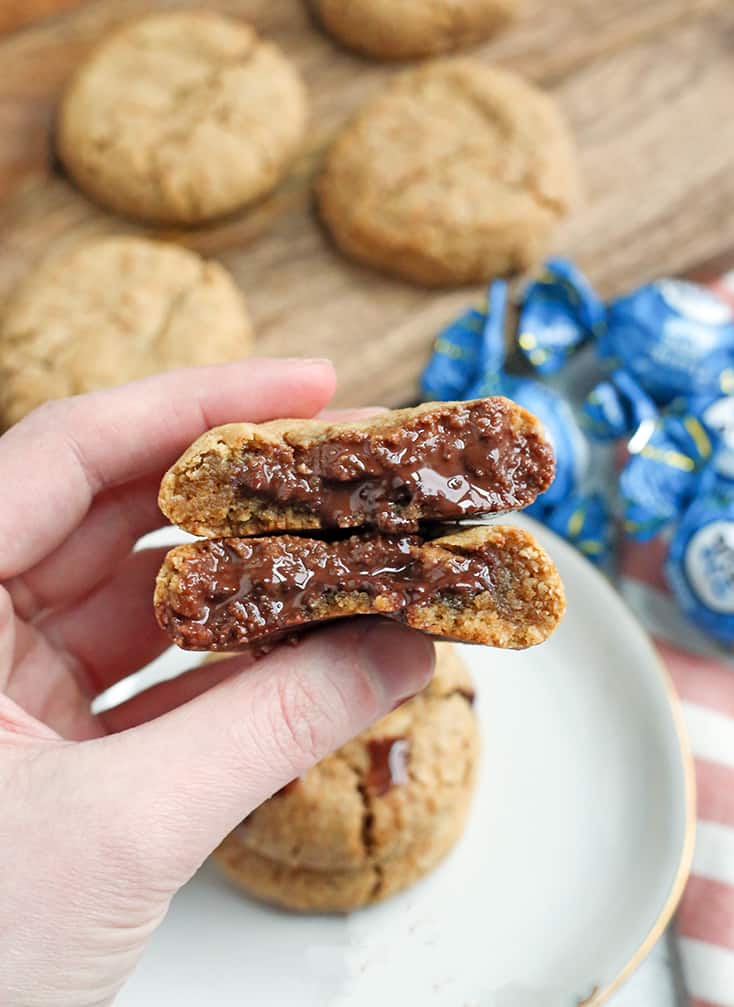 a hand holding a chocolate stuffed cookies with the gooey chocolate showing 