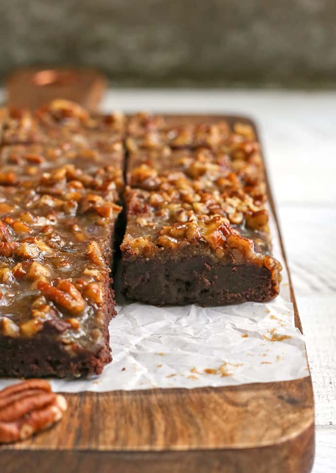 a cutting board with squares of paleo pecan praline brownies on it