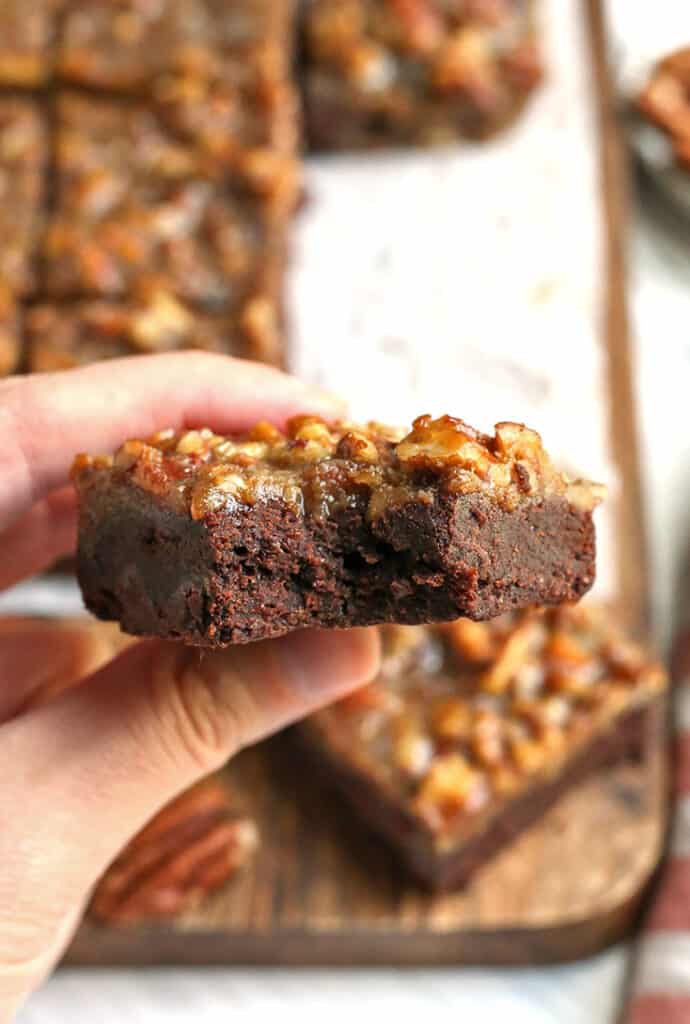a hand holding a fudgy paleo brownie with a pecan topping