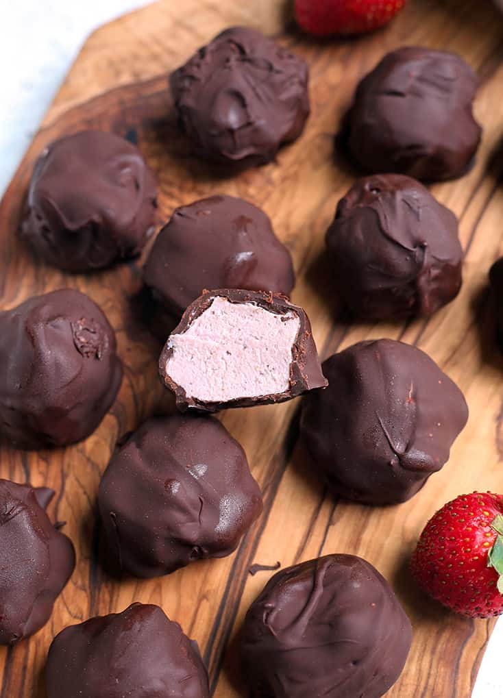 vegan paleo strawberry cheesecake bites on a cutting board with the inside of one showing 