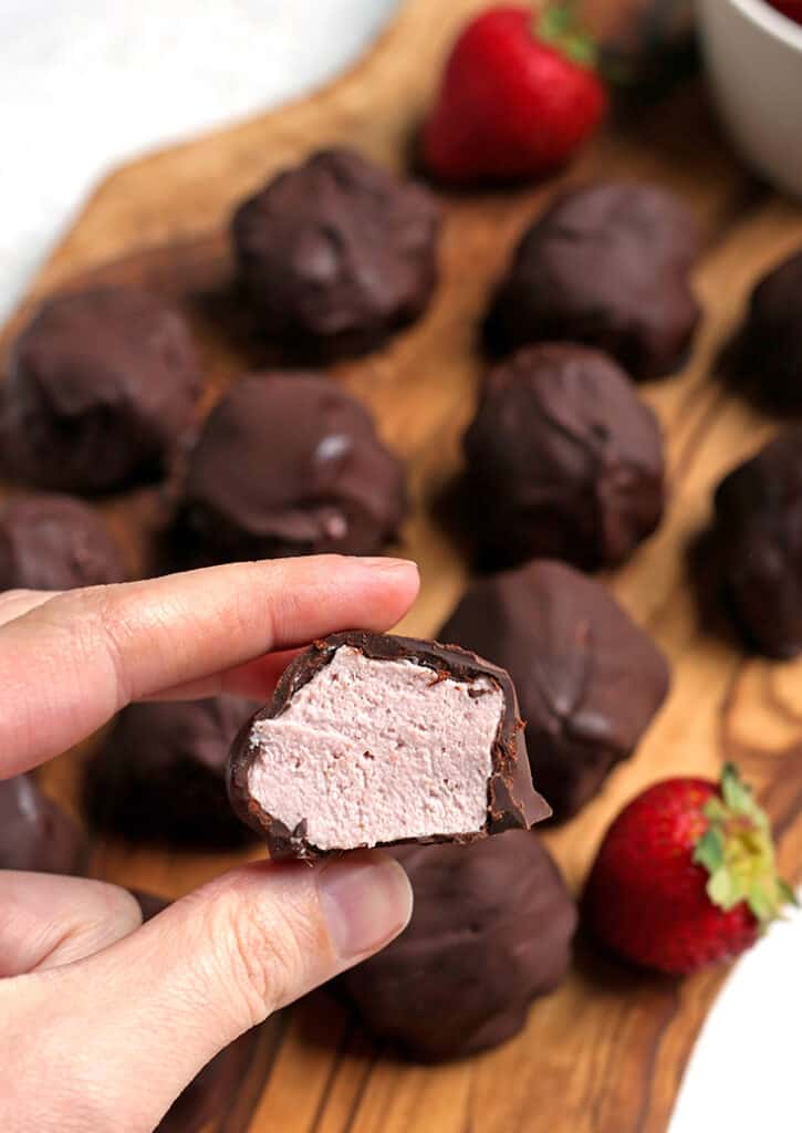 a hand holding a paleo strawberry cheesecake bite