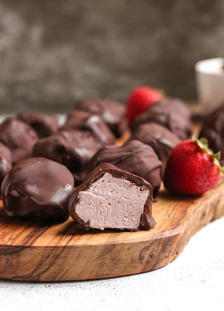 vegan paleo strawberry cheesecake bites on a cutting board with the inside showing with one