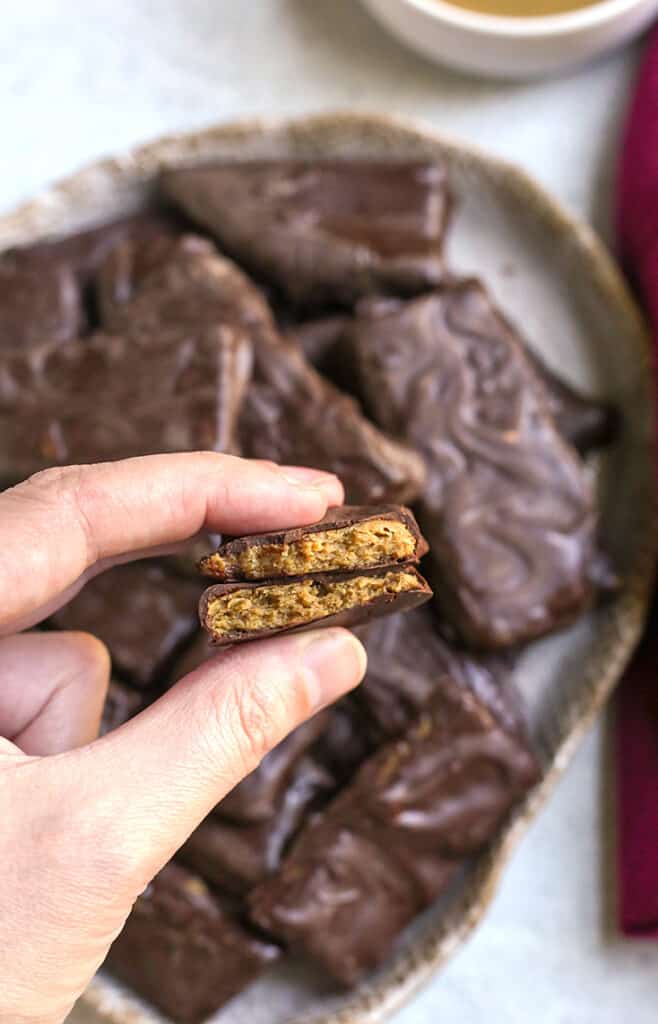 a hand holding a paleo vegan butterfinger candy bar, showing the inside