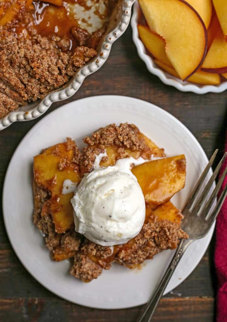 vegan paleo peach crisp on a plate with ice cream on top