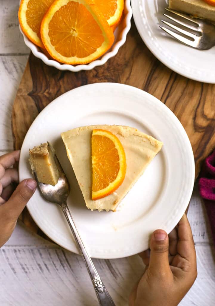 little hands holding a plate with a piece of paleo orange creamsicle cheesecake 