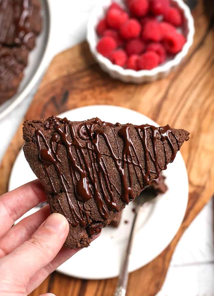 a hand holding a chocolate scone showing the chocolate drizzle