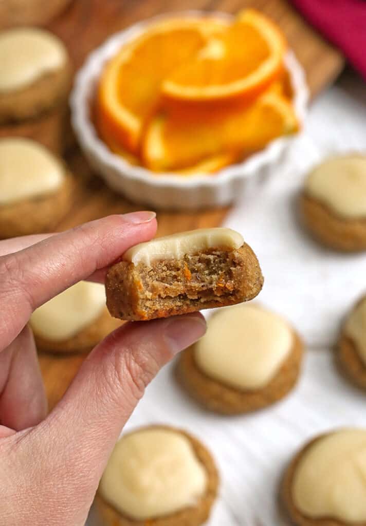 a hand holding a paleo vegan orange cookie with a bite taken out 